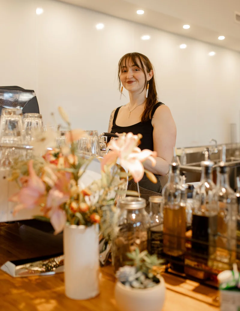 Aja smiling behind the coffee bar in Give & Take’s current space
