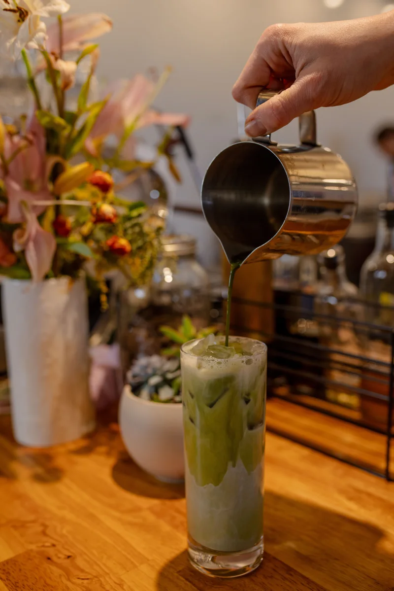 Matcha being poured into an iced drink on the bar