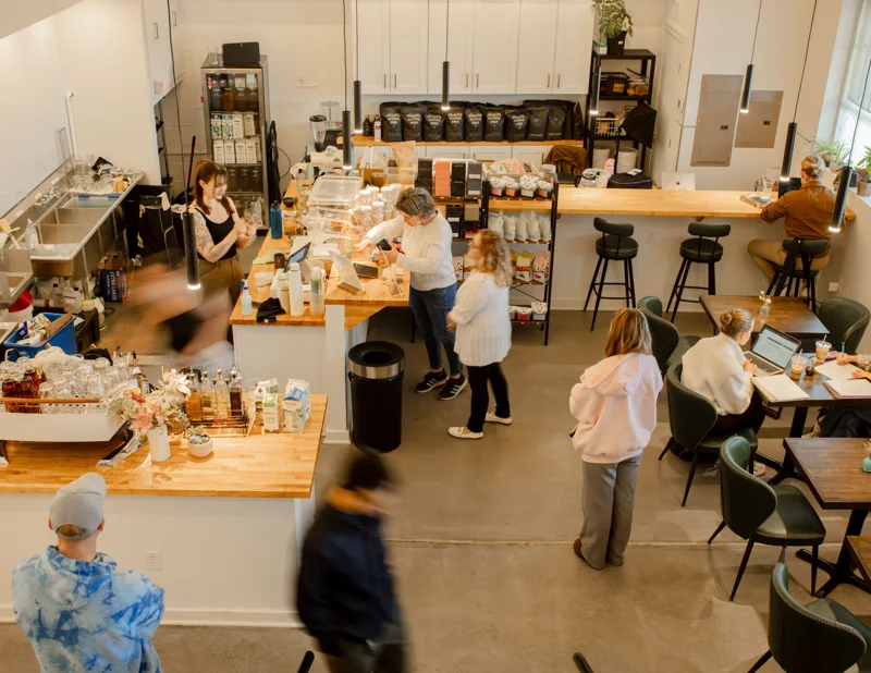 Customers and baristas in the bright Give & Take café, photographed from upstairs